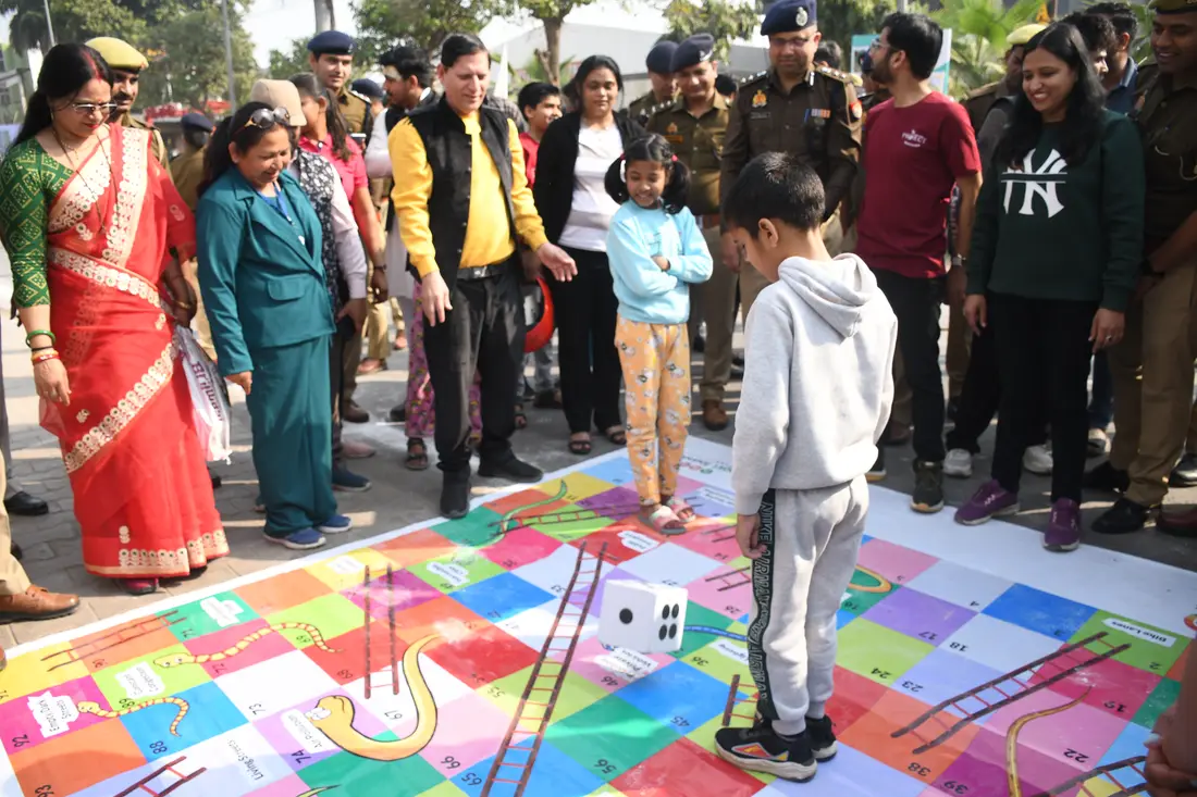 Families playing a giant snakes-and-ladders game painted on the road