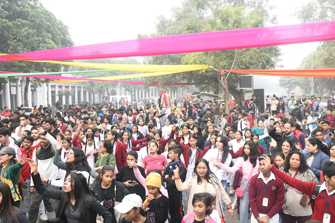 A vast crowd with arms raised under colourful ribbons on a car-free street