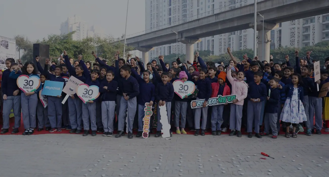 School children holding 30 km/h speed limit signs beside a busy road