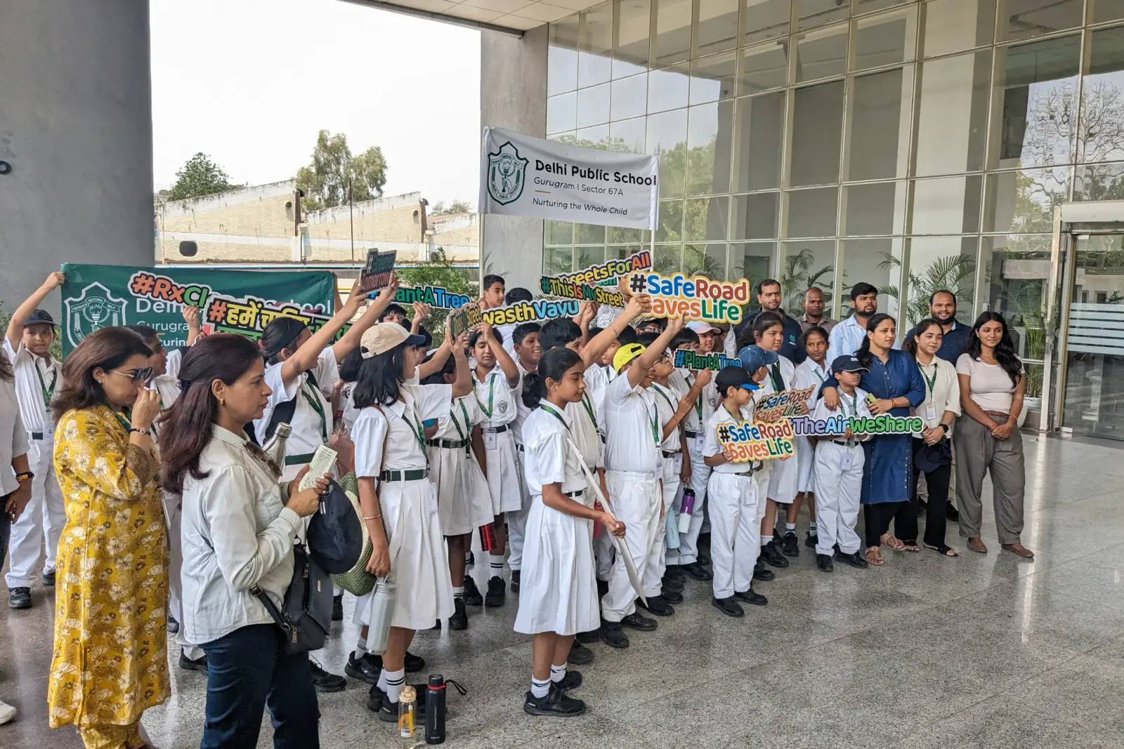 School children holding placards with volunteers outside their school